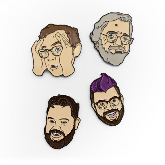 Four enamel pins with black metal plating. Griffin has his hands up looking to the left. Clint is staring steely at the viewer. Travis has a purple mohawk and is smiling. Justin is smiling with his beard.