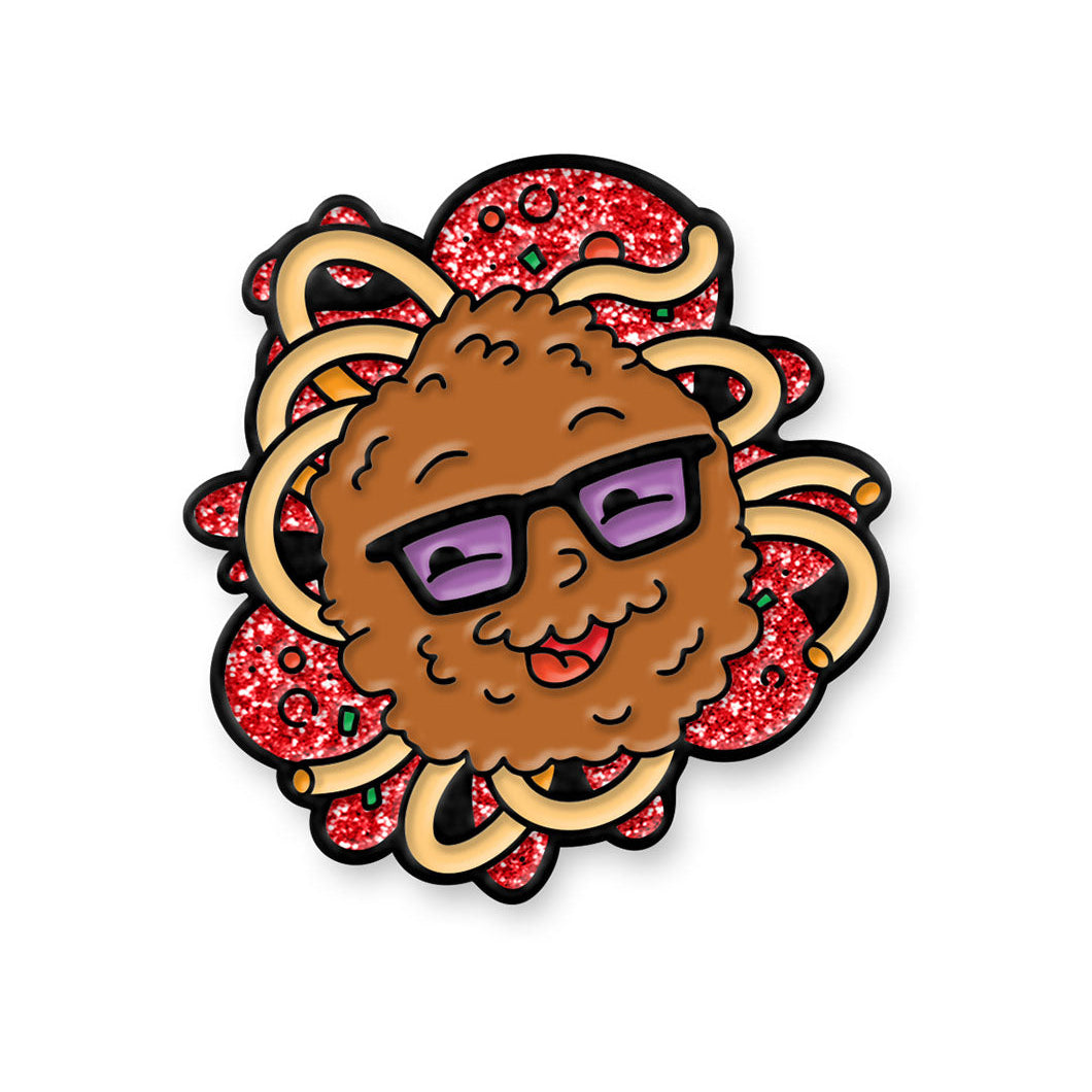 A mockup of a soft enamel pin featuring Travis as a meatball on a splash of spaghetti noodles and glittery sauce.