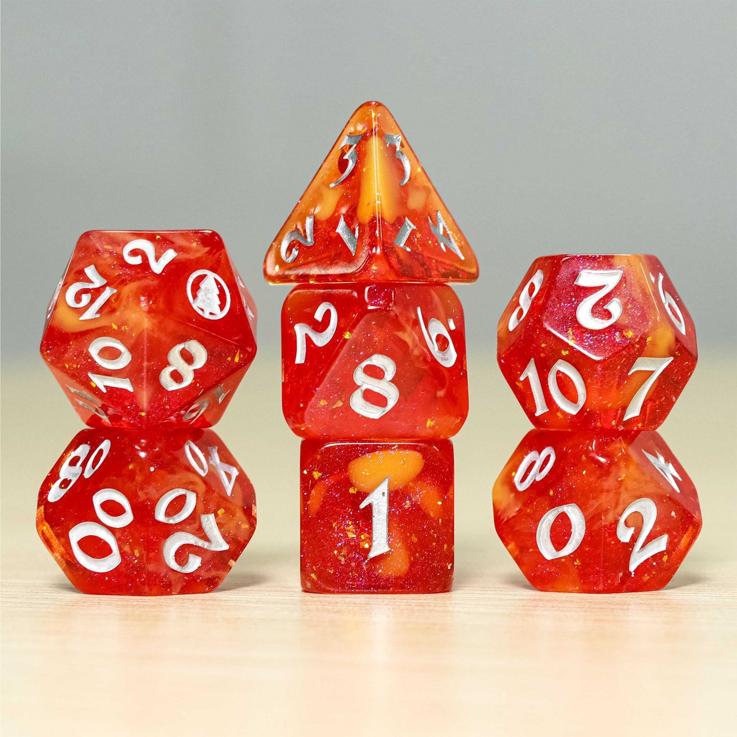 Image of an orange dice set with silver lettering. The dice have yellow veins and glitter running through the center of them. The 20 on the D20 is a silver pine tree in a circle.