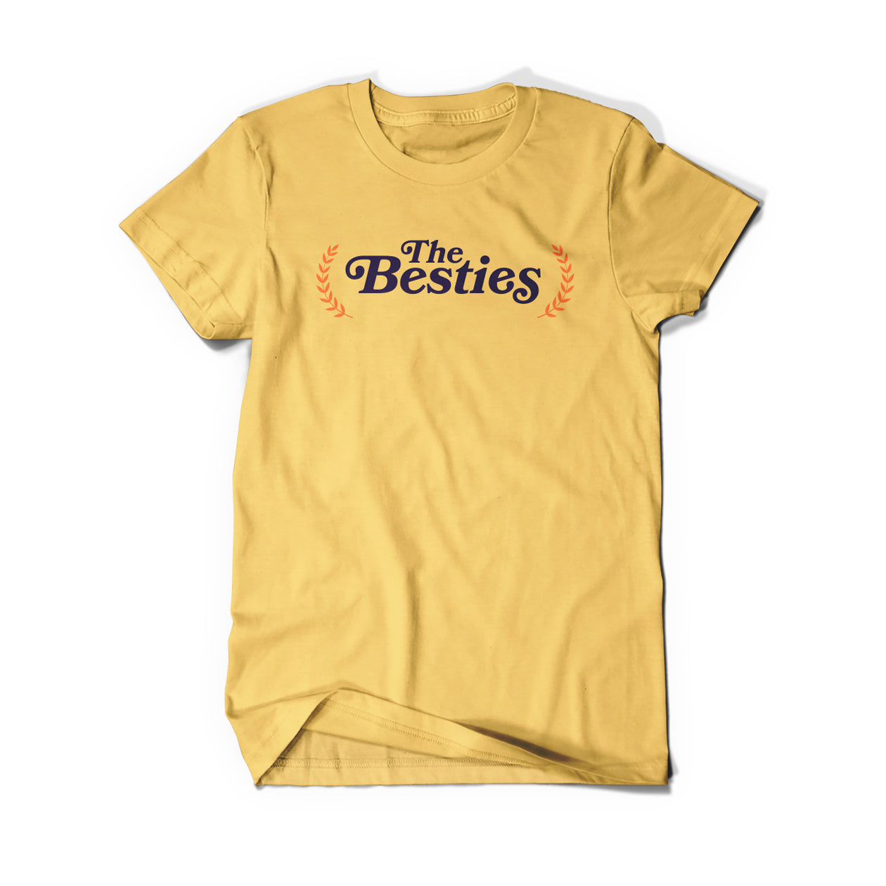 A gold shirt that says, "The Besties" in black serif font with an orange laurel on either side.