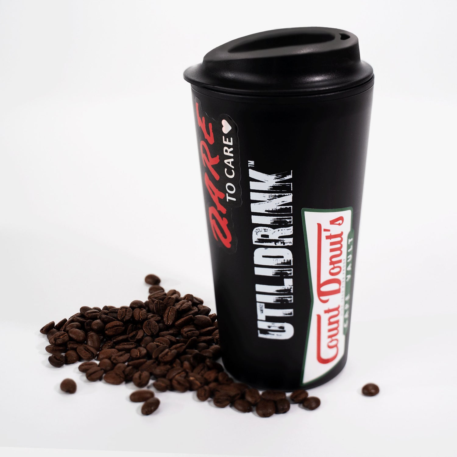 Photo of a black drink tumbler with a plastic lid. On the side it says, “UTILIDRINK” in white distressed lettering. There are some McElroy stickers on it and a pile of coffee beans beneath it.