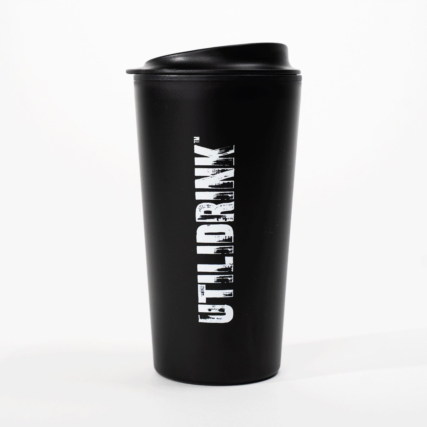 Photo of a black drink tumbler with a plastic lid. On the side it says, “UTILIDRINK” in white distressed lettering. 