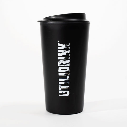 Photo of a black drink tumbler with a plastic lid. On the side it says, “UTILIDRINK” in white distressed lettering. 