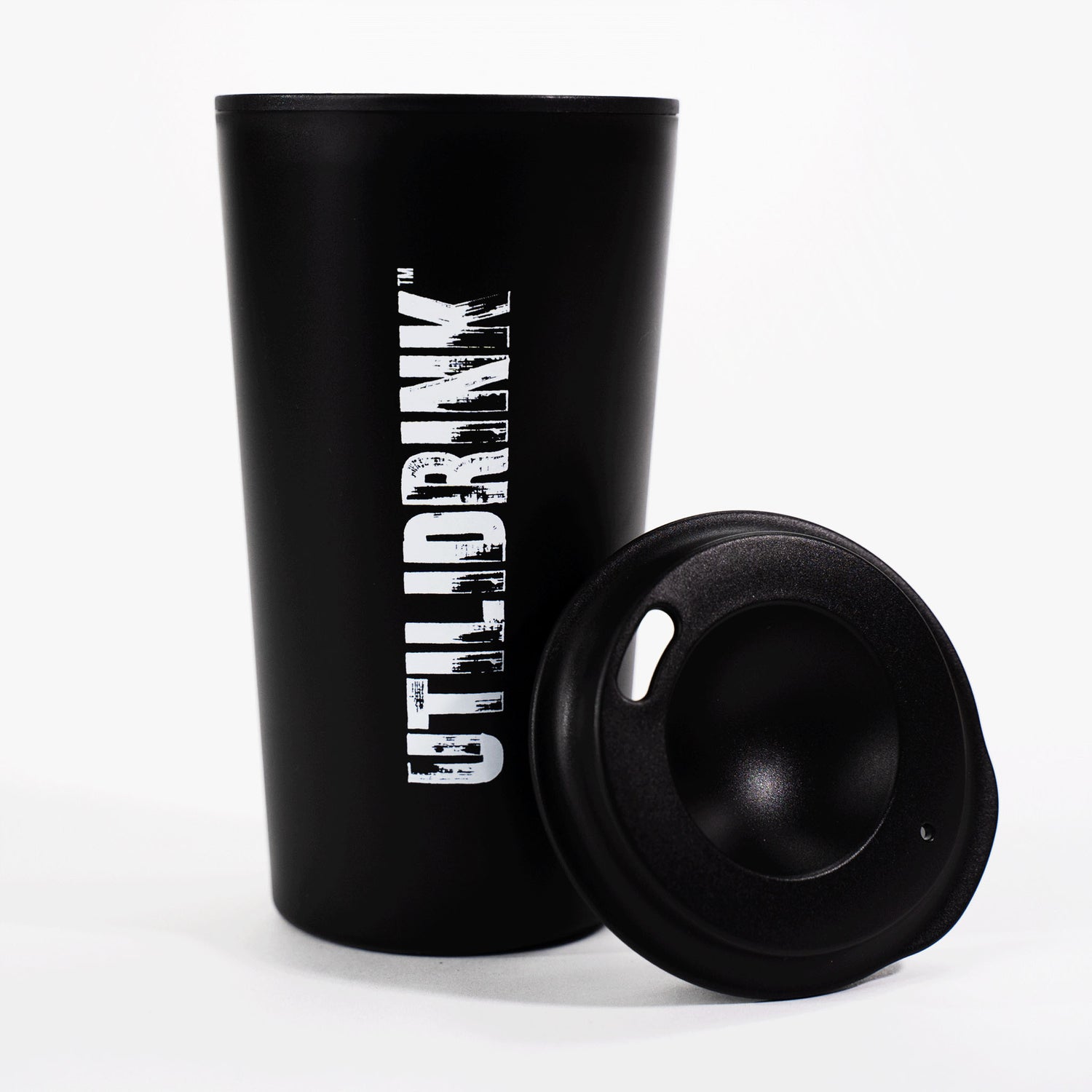 Photo of a black drink tumbler with a plastic lid. On the side it says, “UTILIDRINK” in white distressed lettering. 