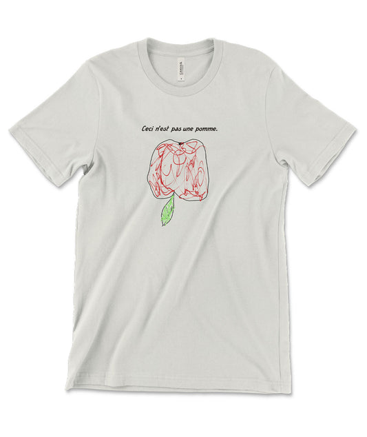 A mockup of a vintage white colored shirt with a scribbly illustration of an upside-down apple and the caption "Ceci n'est pas une pomme."