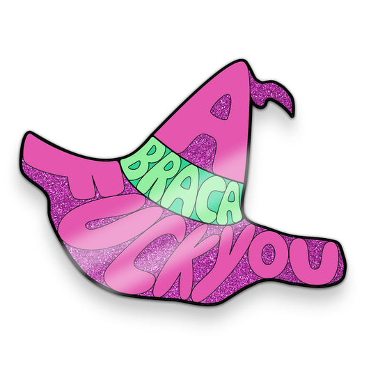 A fuschia sticker of a mage hat. Parts of the sticker are glitter. In the shape of the hat are the words, “Abraca-fuck you”. There is a green sash across the hat.