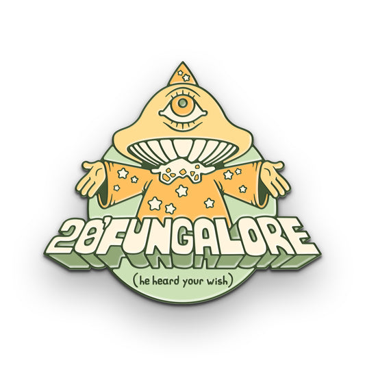 A pastel yellow and green enamel pin of a mushroom wizard with one eye in the center of his cap. He is holding his arms open and has stars on his robe. Below his it says, “20’Fungalore (he heard your wish).”