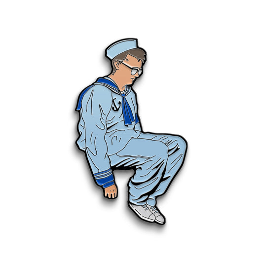 An enamel pin of sad Little Sailor Man Griffin. He is wearing his white sailor suit and hat with white sneakers.