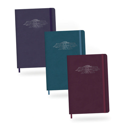 Three notebooks embossed with the TAZ logo. From left to right, they are teal, purple, and maroon. Each one has an elastic band holding it shut.