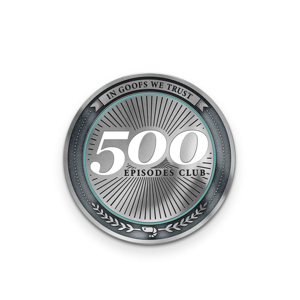 A silver coin that says "500 episodes club" in the center with black rays coming off if it. There is a border that says, "In goofs we trust". At the bottom of the coin is two laurels with a shrimp in the middle and a border of small dots.
