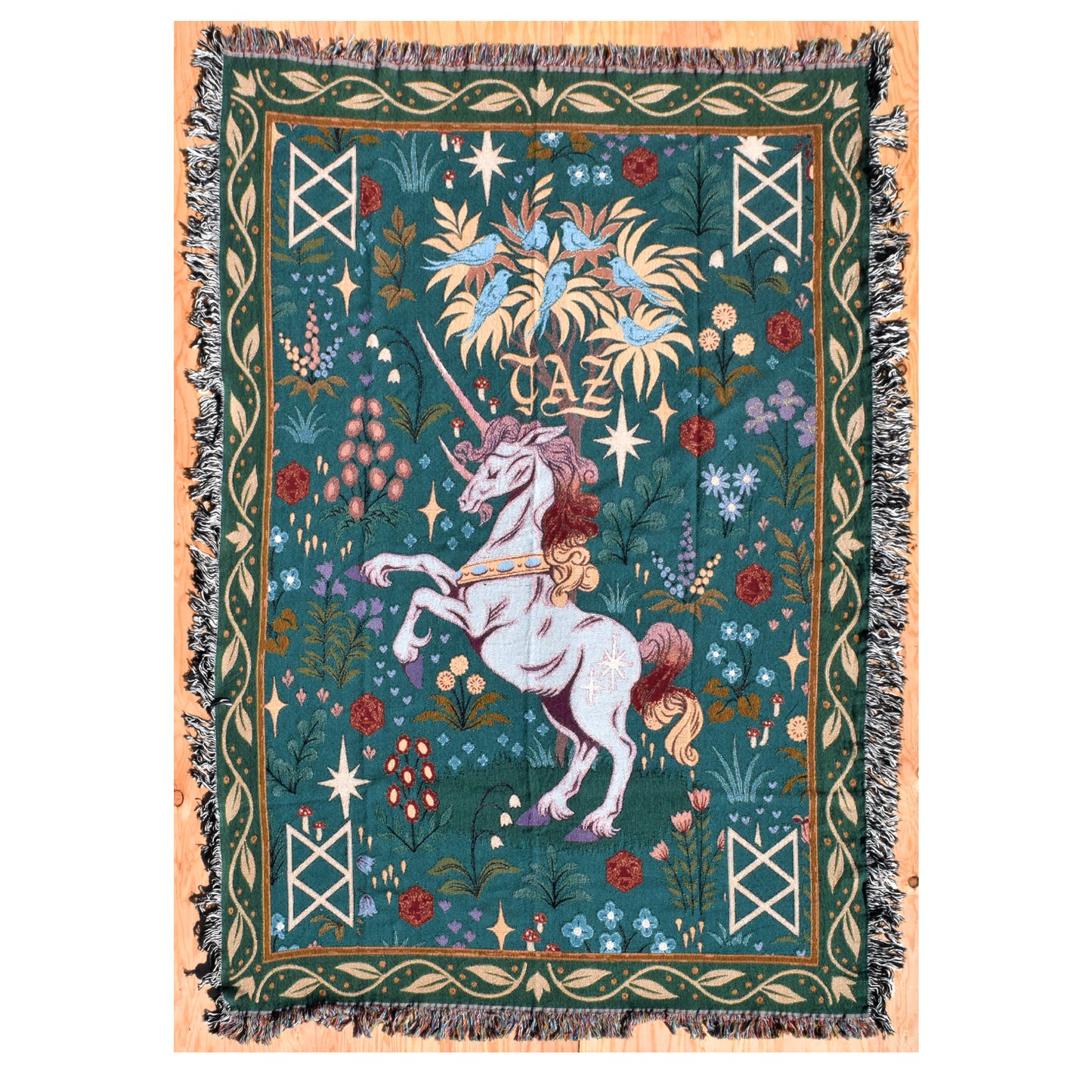 Photo of a teal and green tapestry blanket with Garyl in the center. He’s rearing back on his hind legs and has a flowing mane and tail. There are flowers around him. Above him is a tree with blue birds. There is a B.o.B. rune in each corner.