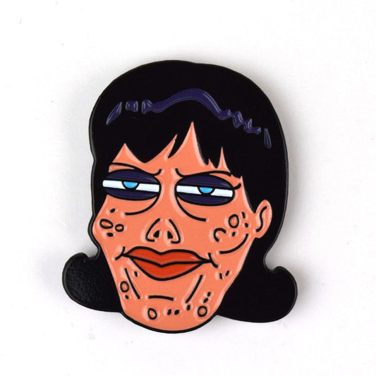 An enamel pin of a face with blemishes and dark circled blue eyes. It has thin black eyebrows and a black bob that curls up at the ends.