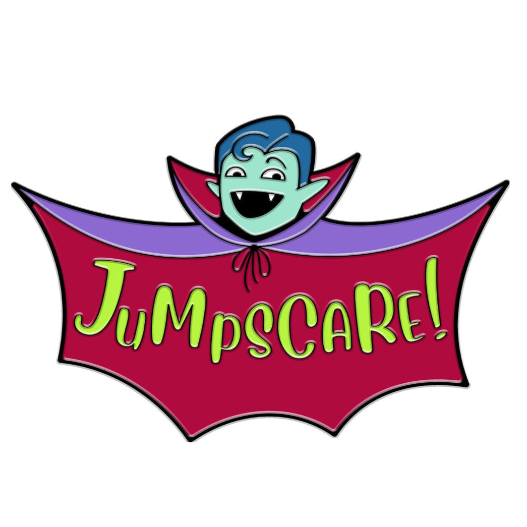 An enamel pin of Justin as a vampire with teal skin, pointed ears, fangs, and a bat-like cape that says “Jumpscare!” on the inside. The cape is purple with a maroon inside. 