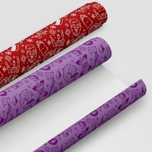 Two rolls of wrapping paper: one a red MBMBaM roll and the other a purple TAZ roll. The red has illustrations of the haunted doll, burning candles, a ghost wearing a knitted hat, a shrimp in a scarf, and a snake in a sweater. The purple roll has illustrations of Magnus’s axe wearing a scarf, Taako’s hat under an open umbrella, the Extreme Teen Bible with a mitten on it, a d20, and Stephen in his glass ball. 
